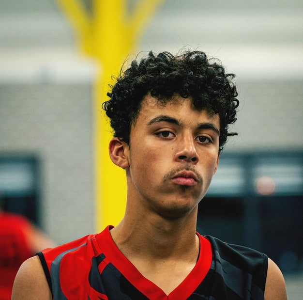 A close-up portrait of Jose Martinez during a Kings League USA game. He is captured in a moment of intense concentration, showcasing his determination and focus. The lighting highlights the texture of his jersey and the sweat on his brow, conveying the physical demands of the sport.