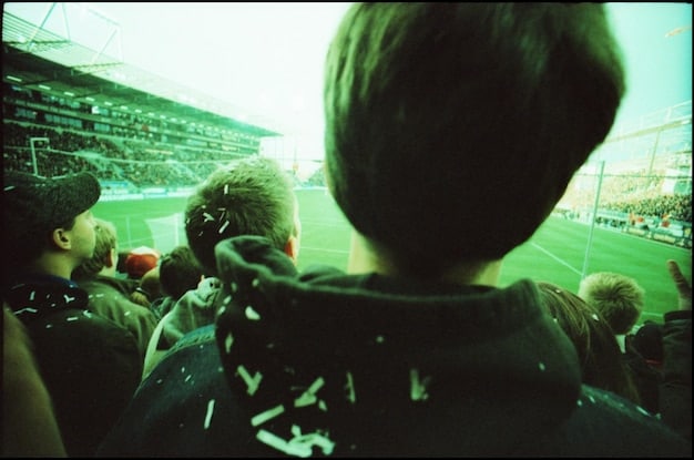 An action shot that shows players in full game mode during a King's League USA match. The image should capture the intensity of competition with engaged players and fans in the background.